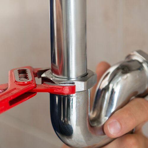 A Plumber Tightens a Pipe.
