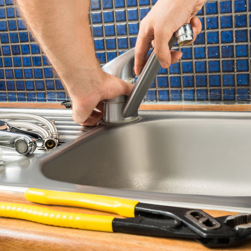 A Plumber Repairs a Faucet.