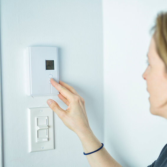 Woman adjusting heater in house